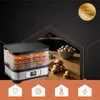 A food dehydrator filled with sliced fruits and vegetables, placed on a wooden table next to a bowl of mushrooms and some loose mushrooms. The background is dark with geometric lines, and a gold award seal is visible in the upper right corner. Below the pr Náhled obrázku produktu