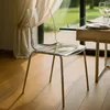 A transparent chair is placed next to a dining table in a well-lit room with a large window overlooking a garden. Produktbild-Vorschau