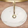 A top-down view of a marble-patterned sink with a gold faucet. Produktbild-Vorschau