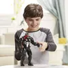 A young boy is holding a Venom action figure in a room. Produktbild-Vorschau