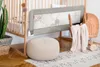 A nursery scene with a crib, a bed rail, a pouf, and a basket with a blanket. Produktbild-Vorschau