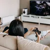 A couple playing video games on the couch in a living room. Podgląd zdjęcia produktu