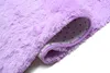 A close-up view of a rolled-up violet rug, showing the fluffy texture of the top and the patterned underside with a purple border. Anteprima dell’immagine prodotto