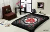 A blanket with a floral pattern is laid out on a floor in a room with a chair and a small table. Produktbild-Vorschau