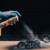 A gloved hand sprays black paint onto a car part. Anteprima dell’immagine prodotto