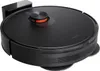 A black robot vacuum cleaner with an orange accent, shown from a slightly elevated side angle. It is positioned on a white background with its charging dock visible on the left. Voir les images du produit