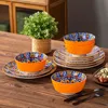 A table setting with a set of ceramic dishes, including plates and bowls, arranged around a small potted plant. Náhled obrázku produktu