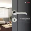A close-up of a door handle and lock on a dark gray door, with a blurred interior scene in the background. Produktbild-Vorschau