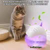 A cat sits on a wooden floor next to a purple air purifier with leaves floating around it. Produktbild-Vorschau
