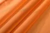 A close-up, abstract view of folded orange fabric, likely curtains, showing texture and folds. Produktbild-Vorschau