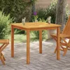A wooden table and chairs set up on a patio with greenery in the background. Produktbild-Vorschau