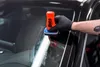 A person's hand wearing a black glove is applying a product to a car windshield. Produktbild-Vorschau