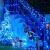 A festive outdoor Christmas decoration scene with blue lights, a decorated tree, stockings, and gifts. Produktbild-Vorschau