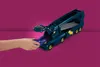 A child's hand is placing a blue toy car into a dark blue toy truck. Anteprima dell’immagine prodotto