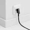 A black telephone cable with an RJ11 connector is plugged into a white wall socket. Produktbild-Vorschau