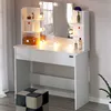 A white vanity table with a mirror and LED lights, featuring shelves with various cosmetic products and a storage box. A patterned stool is placed in front of the table. Anteprima dell’immagine prodotto
