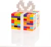 A gift box made of colorful LEGO bricks with a white LEGO bow on top, reflected on a white surface. Produktbild-Vorschau
