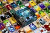 A board game box and cards are spread out on a wooden surface. Podgląd zdjęcia produktu
