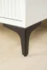 A close-up of a black metal furniture leg attached to a white cabinet. Podgląd zdjęcia produktu