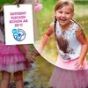 Two young girls are playing in the mud, covered in dirt. One girl is smiling and looking at the camera, while the other is partially visible in the foreground. Produktbild-Vorschau