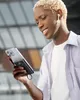 A young man is holding a smartphone with a power bank attached, looking at the phone screen and smiling. Produktbild-Vorschau