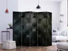 A modern living room with a black tufted room divider, a white sofa, and decorative lamps. Produktbild-Vorschau