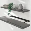 Two gray shelves mounted on a light gray wall. The top shelf has books, a plant, and a vase. The bottom shelf has a black bracket attached. Anteprima dell’immagine prodotto