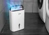 A white dehumidifier is shown in a bathroom setting next to a washing machine. Náhľad obrázku produktu