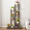 A multi-tiered plant stand with various potted plants on display against a white wall. Náhled obrázku produktu