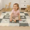 A baby is sitting on a puzzle mat with dinosaur designs in a nursery or playroom. Náhľad obrázku produktu