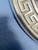 A close-up of a decorative wall relief with a Greek key pattern in white and gold. Náhľad obrázku produktu