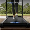 A person is walking on a treadmill indoors, with a view of trees and a patio through a large window. Produktbild-Vorschau