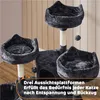 A multi-level cat tree with several platforms and a dangling toy, set against a light-colored wall and floor. Produktbild-Vorschau