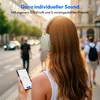 A woman wearing headphones and holding a smartphone on a city street. Produktbild-Vorschau