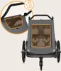 A close-up view of a gray child trailer with orange trim, showing a magnified section of the sunshade. Produktbild-Vorschau