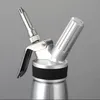 A silver whipped cream dispenser with a black grip is shown against a plain gray background. Produktbild-Vorschau