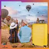 A couple sits on a blanket in a landscape with hot air balloons in the sky and unique rock formations. Anteprima dell’immagine prodotto