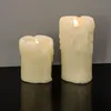 Two LED candles with dripping wax effect are shown on a black surface against a gray wall. Produktbild-Vorschau