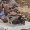 A person is using tongs to place food on a portable grill. Anteprima dell’immagine prodotto