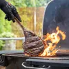 A large tomahawk steak is being grilled over open flames on a barbecue. Produktbild-Vorschau