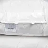 A close-up of a white pillow inside its clear plastic packaging, with a label attached. Produktbild-Vorschau