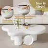 A white, irregularly shaped coffee table is shown in a living room setting, with close-up insets highlighting its features. Voir les images du produit
