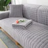 Grauer gesteppter Sofabezug auf einem Sofa mit passendem Wurfkissen und gefalteter Decke, darauf eine rosa Rose Náhľad obrázku produktu