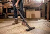 A person is vacuuming wood shavings in a workshop. Anteprima dell’immagine prodotto