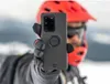 A person wearing a helmet and goggles holds up a phone case in a snowy environment. Produktbild-Vorschau