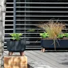 Two planters with plants on a wooden deck, with a modern slatted wall in the background. Produktbild-Vorschau
