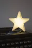 A glowing star-shaped lamp sits on top of an old typewriter. Produktbild-Vorschau