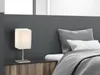 A bedside table with a lamp and pillows on a bed. Produktbild-Vorschau