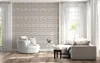 A modern living room with a textured wall, a white armchair, and a sectional sofa. Anteprima dell’immagine prodotto
