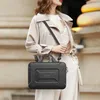 A woman is walking outdoors, carrying a black laptop bag. Náhled obrázku produktu